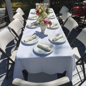 A catering table set with white plates and white napkins.
