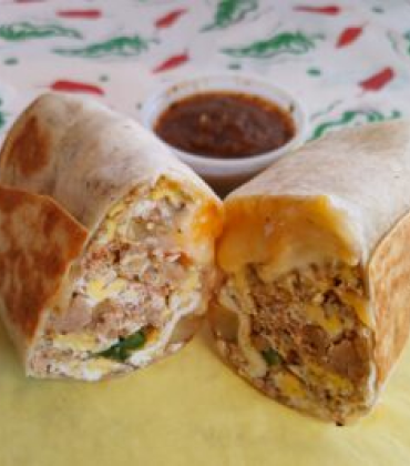 A burrito with eggs and salsa on a yellow napkin.