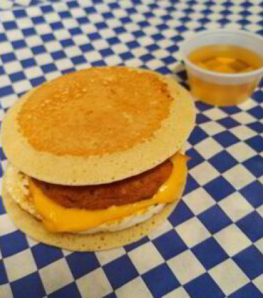 A pancake with eggs and cheese on a checkered tablecloth.