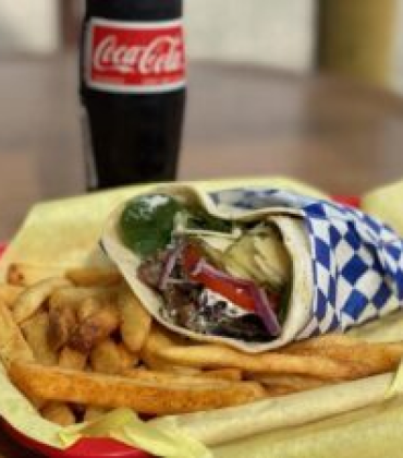A gyro sandwich with fries and coke on a plate.