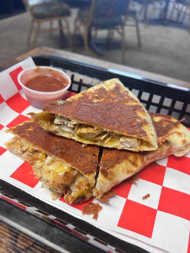 A quesadilla is sitting on top of a red and white checkered tray.