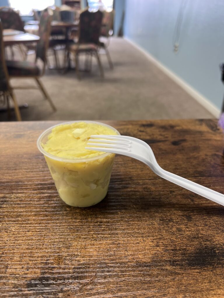 A cup of food with a fork sitting on a table.